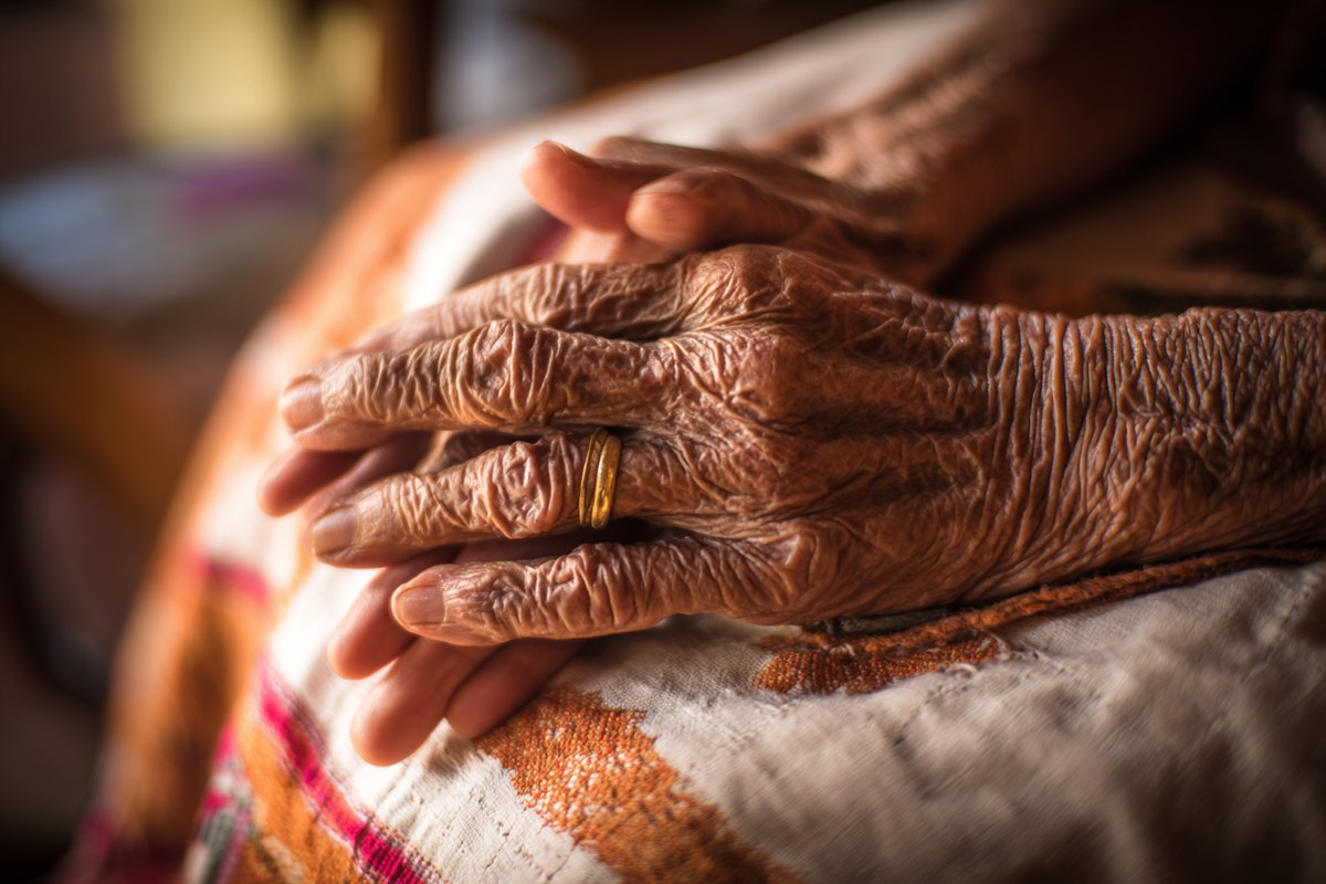 Las manos de una persona mayor, acompañadas por las de alguien más